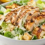 Ultimate Caesar Salad with Grilled Chicken served with crisp romaine lettuce, juicy grilled chicken, crunchy croutons, Parmesan cheese, and creamy Caesar dressing.