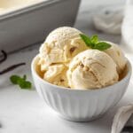 Homemade vanilla ice cream without a machine served in a bowl with three creamy scoops