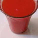 Homemade watermelon juice served in a glass on a white plate