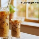 Glass of low sugar iced coffee with milk and ice cubes on a wooden table
