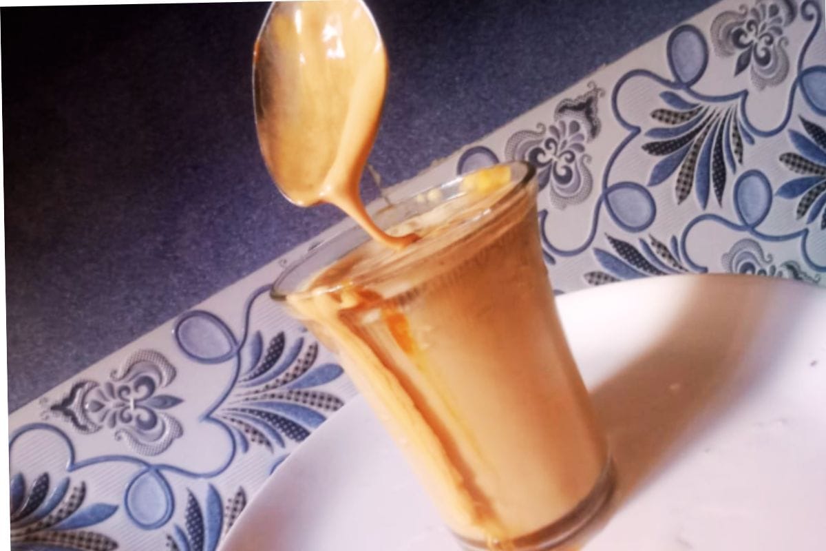 Creamy mocha iced coffee being poured into a glass over ice at home