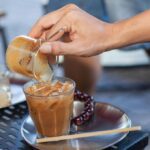 mocha iced coffee being poured over ice in a glass at home