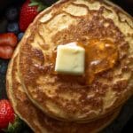 Fluffy pancakes with butter and berries in a skillet.
